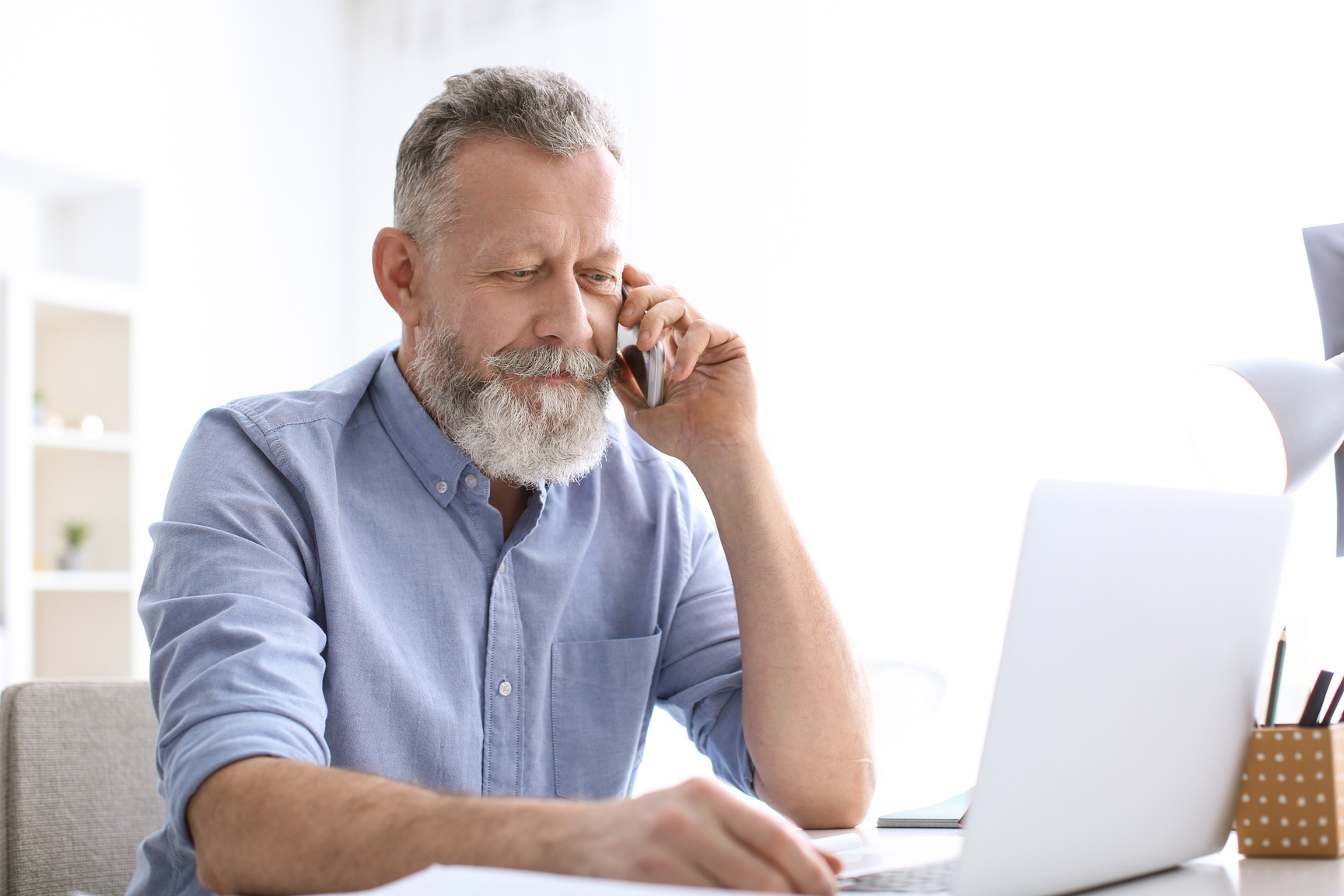 Old Man Talking over His Mobile Phone While Working 